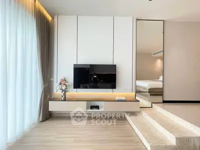 Modern living room with sleek TV unit and elegant decor, featuring a cozy bedroom view.