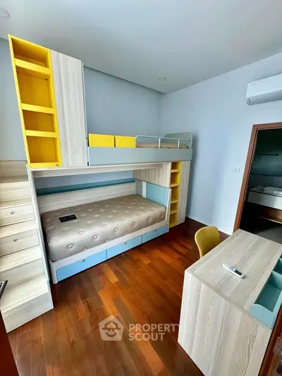 Modern bedroom with bunk bed and study desk, featuring sleek wooden flooring and vibrant yellow accents.