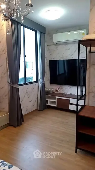 Modern living room with large TV, elegant chandelier, and stylish decor.