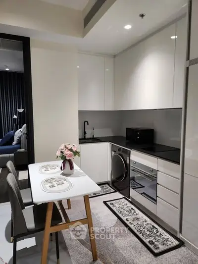 Modern kitchen with sleek cabinetry, dining table, and built-in appliances in a stylish apartment.