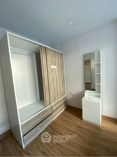 Modern bedroom with sleek wardrobe and mirror on wooden flooring.