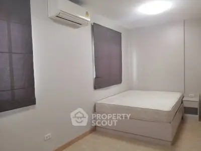 Spacious and well-lit bedroom with a large bed, modern air conditioning unit, and elegant purple window shades, perfect for restful nights.