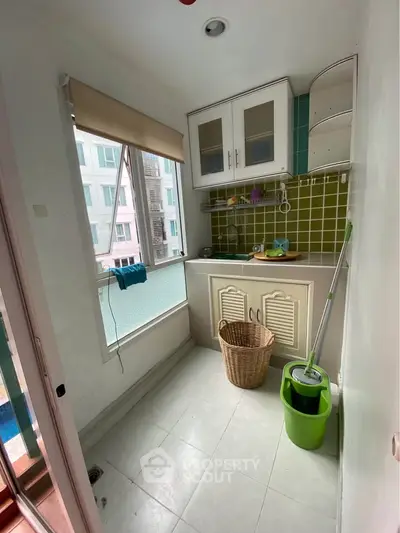 Charming utility room with large window and modern cabinetry in a bright apartment.