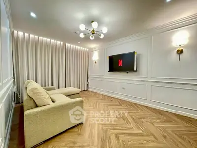 Elegant living room with modern lighting and wall-mounted TV, featuring stylish wood flooring and cozy seating.