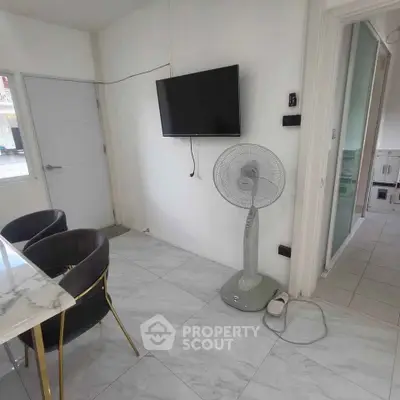 Modern living area with marble flooring, wall-mounted TV, and sleek dining chairs.