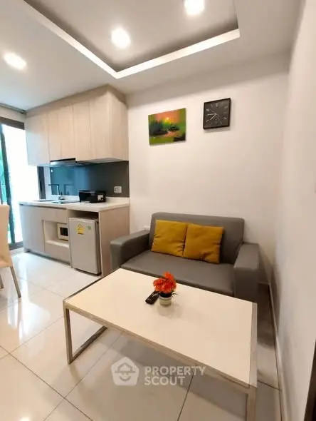 Modern living room with sleek furniture and open kitchen layout.