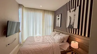 Cozy bedroom with modern decor and wall art, featuring a mounted TV and soft lighting.