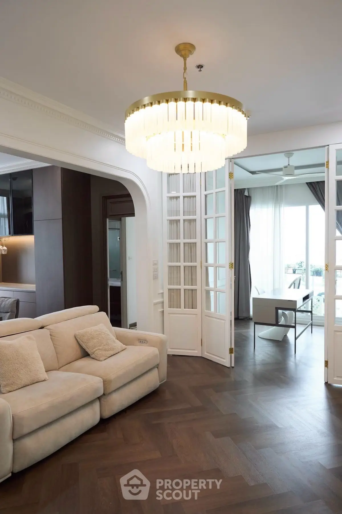 Elegant living room with chandelier and open layout leading to balcony with view.