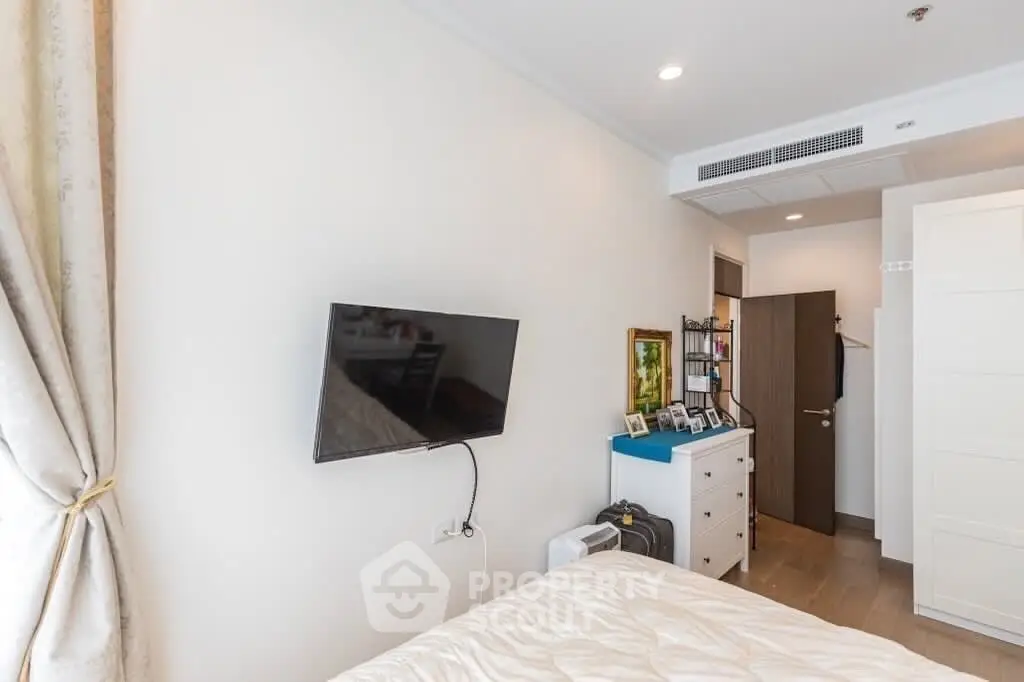 Modern bedroom with wall-mounted TV and stylish decor in a cozy apartment.