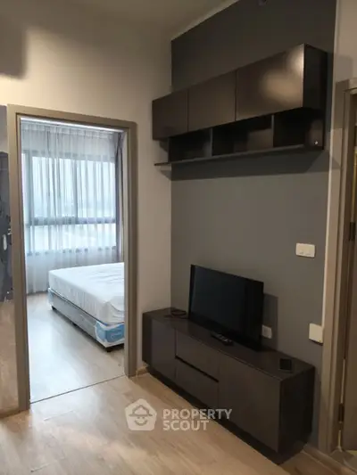 Modern bedroom with sleek storage and TV unit, featuring large window for natural light.