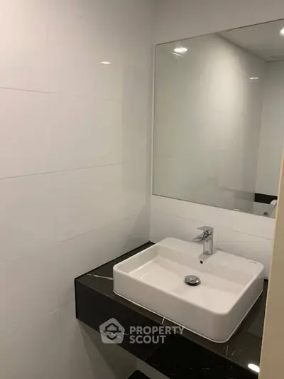 Modern bathroom with sleek sink and large mirror in contemporary apartment.