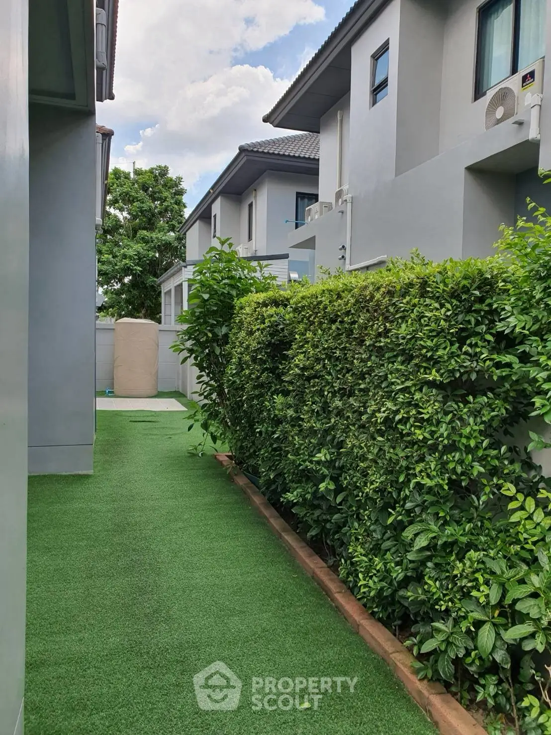 Modern townhouse exterior with lush green garden and hedge