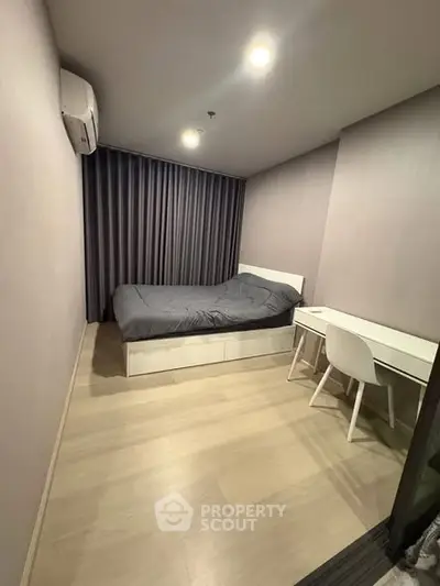 Modern bedroom with sleek design, featuring a cozy bed and functional study area.