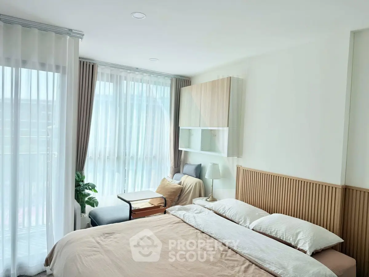 Bright and cozy bedroom with large windows and modern decor, perfect for relaxation.
