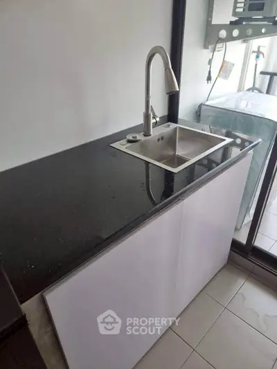 Modern kitchen with sleek black countertop and stainless steel sink, perfect for contemporary living.