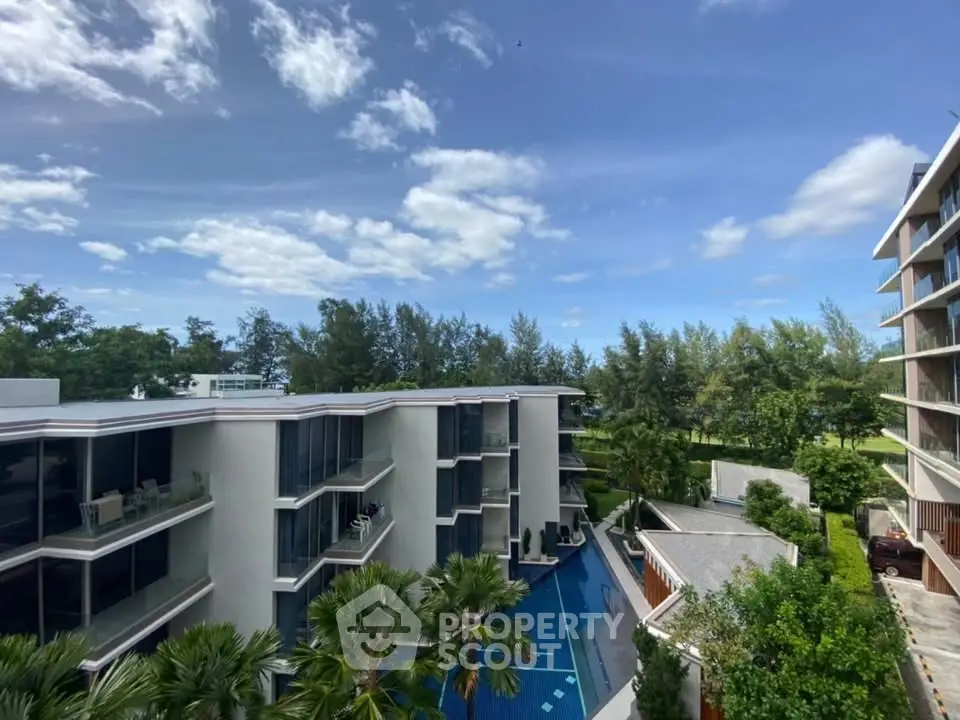 Stunning modern apartment complex with pool and lush greenery under a clear blue sky.
