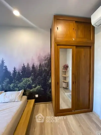 Stylish bedroom with wooden wardrobe and forest-themed accent wall