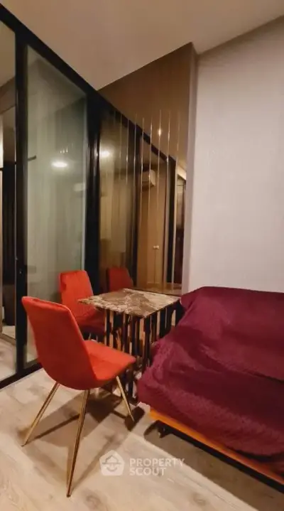 Cozy modern living room with red chairs and glass partition, perfect for stylish urban living.
