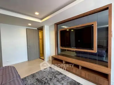 Modern living room with large TV and stylish wooden entertainment center.