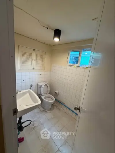 Compact bathroom with white tiles and basic fixtures, ideal for small spaces.