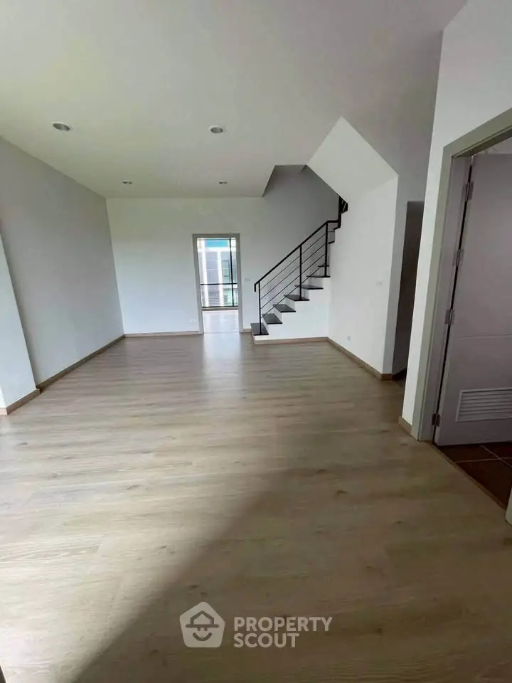 Spacious modern living room with wooden flooring and staircase, perfect for family gatherings.
