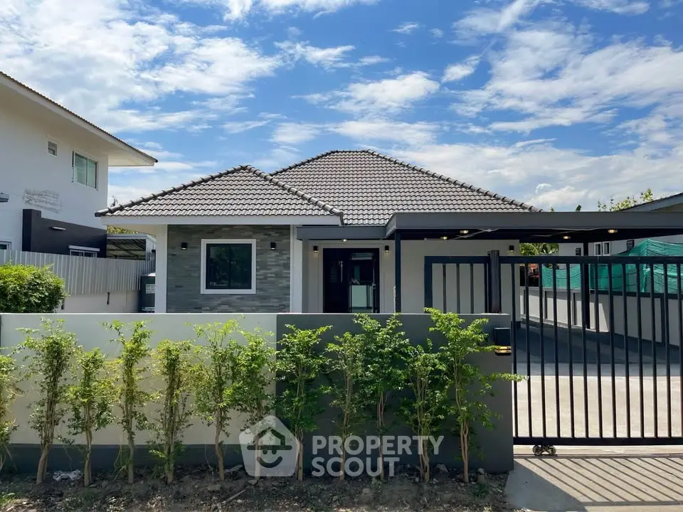 Charming modern house with tiled roof and lush greenery under a clear blue sky.