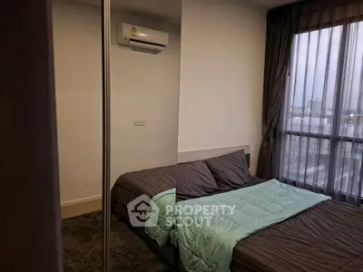 Modern bedroom with large window and mirrored closet, featuring a cozy bed and air conditioning.