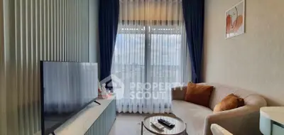 Modern living room with large TV, cozy sofa, and elegant curtains.