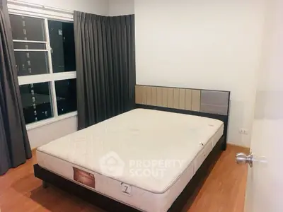 Cozy bedroom with large window and modern bed frame, perfect for urban living.