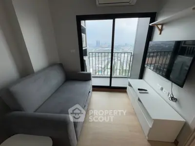 Modern living room with balcony and city view, featuring sleek furniture and a wall-mounted TV.