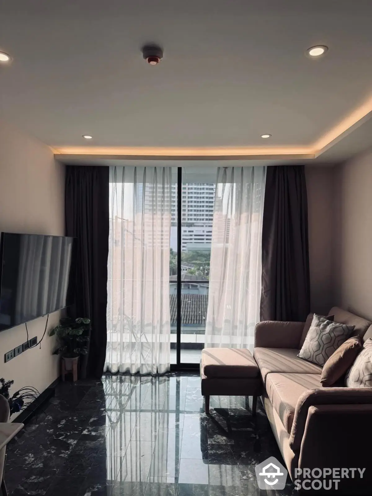 Modern living room with large windows and city view, featuring stylish sofa and sleek marble flooring.