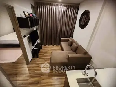 Cozy living room with modern decor and wooden flooring, featuring a comfortable sofa and wall-mounted TV.