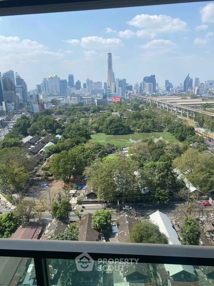 Stunning cityscape view from high-rise balcony overlooking lush greenery and urban skyline.