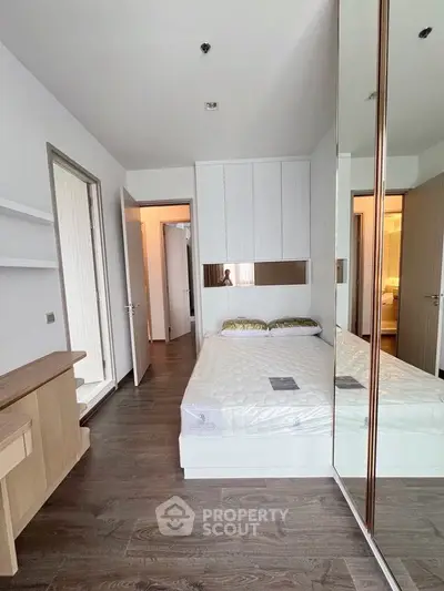 Modern bedroom with mirrored wardrobe and wooden flooring in a stylish apartment.