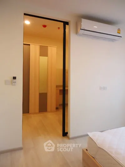 Modern bedroom with air conditioning and wooden flooring, featuring a sliding door to a closet area.