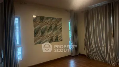 Spacious room with elegant curtains and wooden flooring, perfect for a cozy living space.