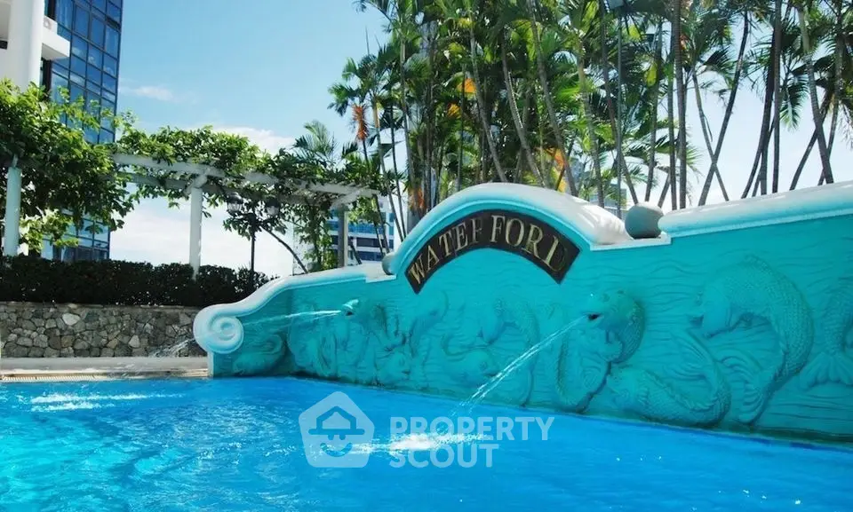 Luxurious pool area with artistic water feature and lush greenery in a high-end property.
