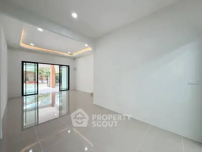 Spacious modern living room with glossy tiled floors and large sliding glass doors opening to a pool view.
