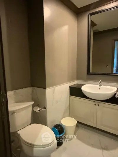Modern bathroom with elegant fixtures and neutral tones, featuring a sleek sink and toilet.