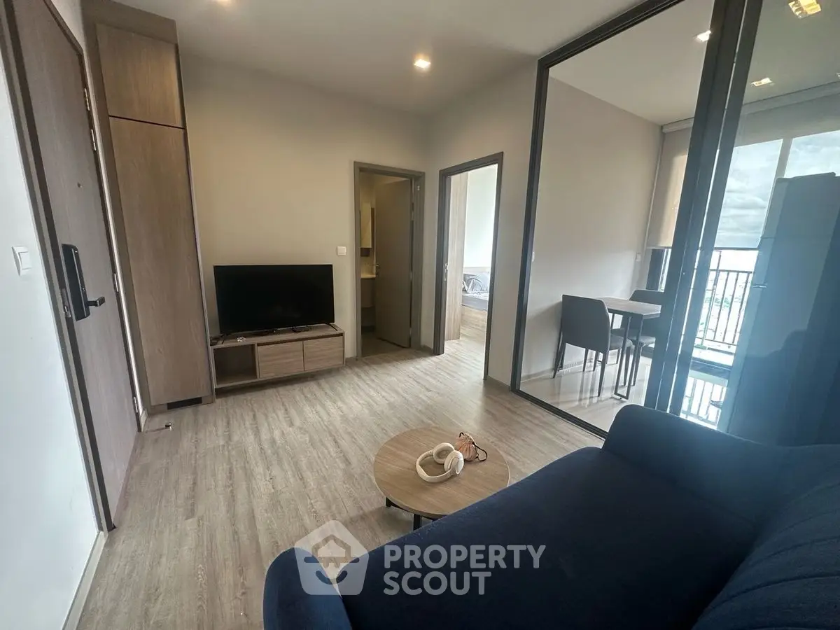Modern living room with sleek design and open layout, featuring a cozy sofa and flat-screen TV.