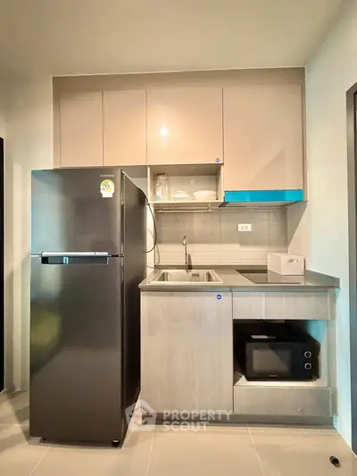 Modern compact kitchen with sleek cabinetry and built-in appliances in a stylish apartment.