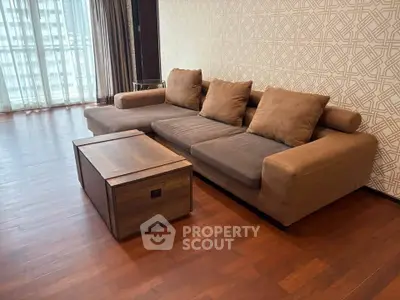 Spacious living room with modern brown sofa and wooden coffee table, featuring elegant patterned wallpaper.