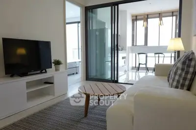 Modern living room with cozy sofa, TV, and open kitchen layout in bright apartment.