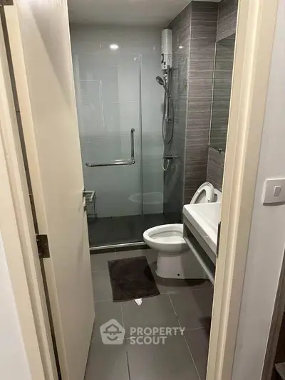 Modern bathroom with glass shower and sleek fixtures in contemporary apartment.