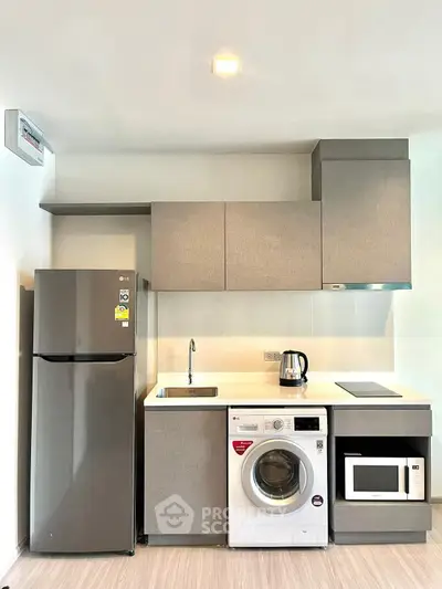 Modern kitchen with sleek appliances including fridge, washing machine, and microwave in compact layout.