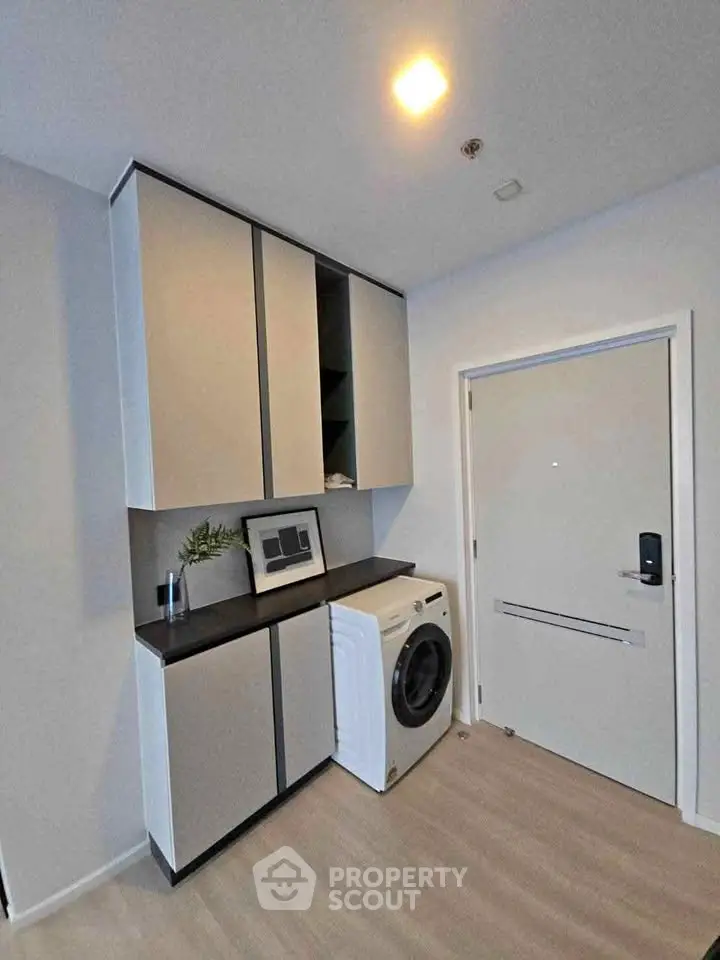 Modern laundry area with sleek cabinets and washing machine in stylish apartment.