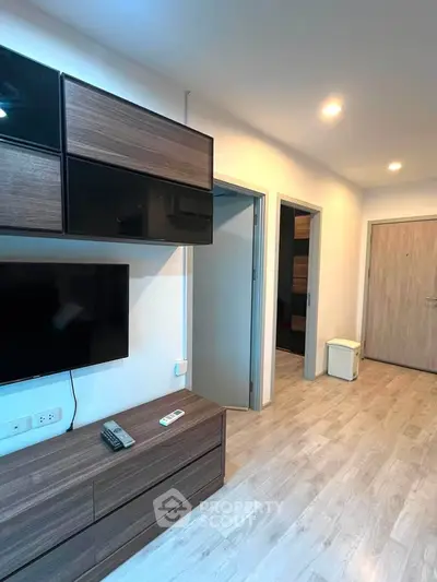 Modern apartment interior with sleek wooden furniture and wall-mounted TV in a bright hallway.