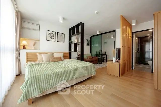 Spacious modern bedroom with wooden flooring and stylish decor in a contemporary apartment.