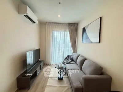 Modern living room with sleek furniture and natural light from large window.