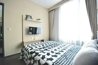 Modern bedroom with large window and wall-mounted TV in stylish apartment.